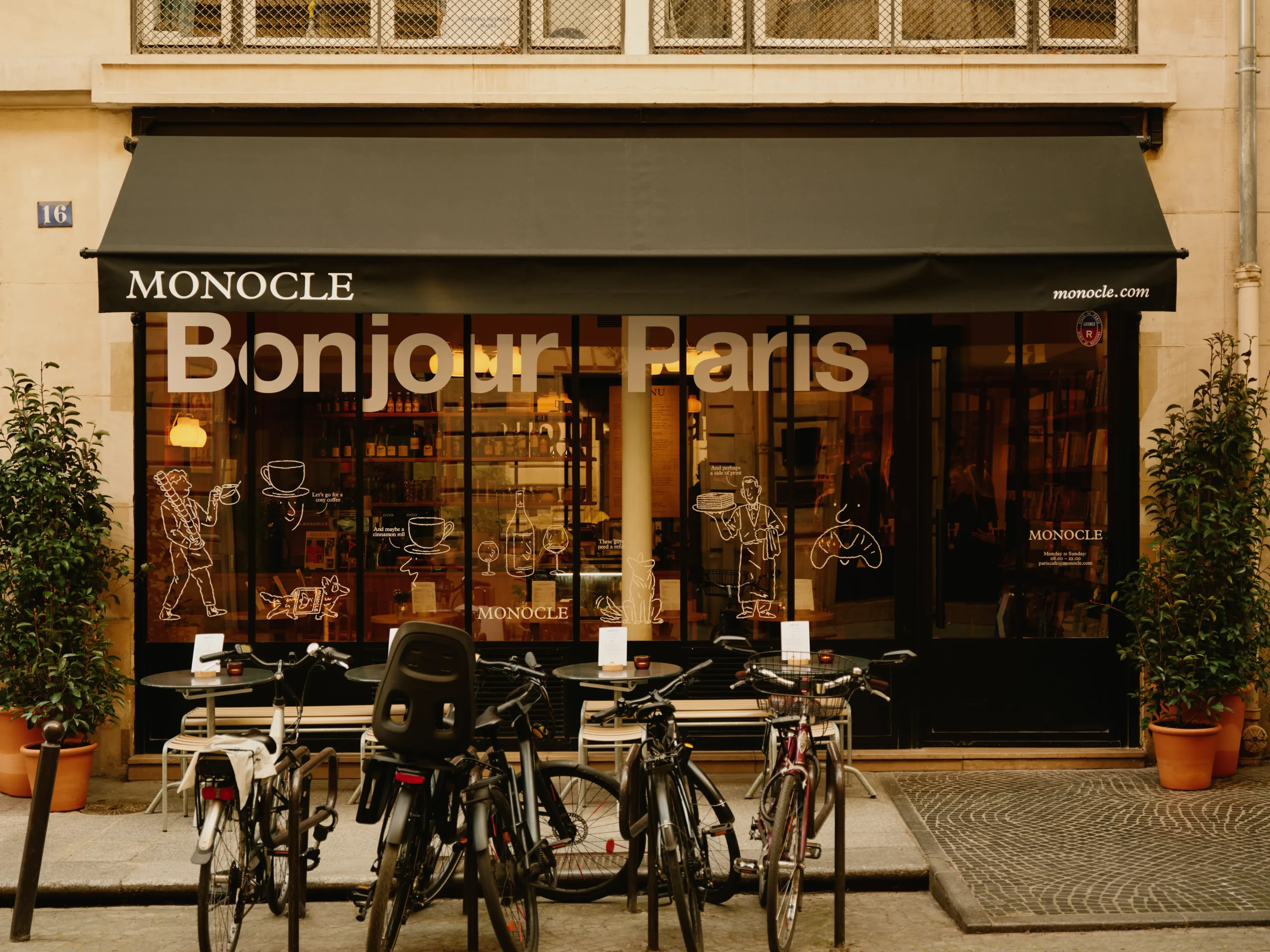 A sleek glass-fronted cafe with black trim carries the words "Bonjour Paris" on its front, as well as branding for high-end magazine Monocle.
